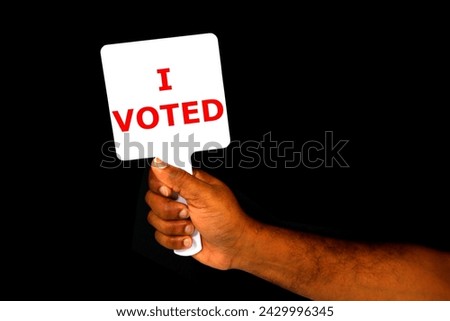 I VOTED Signed board holding hand on black background close-up view, Election concept photography, Motivation for people's to vote on elections, Sign board showing by human hand