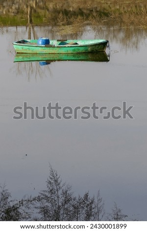 Wooden green colored fishing boat on the lake, reflection of the boat on the water. Authentic wooden boat. Sazlidere Lake, Istanbul, Turkey.