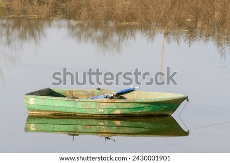 Wooden green colored fishing boat on the lake, reflection of the boat on the water. Authentic wooden boat. Sazlidere Lake, Istanbul, Turkey. Royalty-Free Stock Photo #2430001901