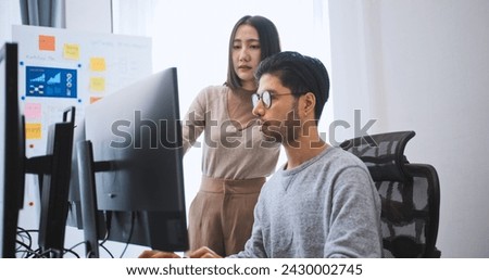 Young adult Asian male, female software developer coding program on desktop computer. Man, woman work from home, remote working, freelance programmer job, smart digital nomad lifestyle concept Royalty-Free Stock Photo #2430002745