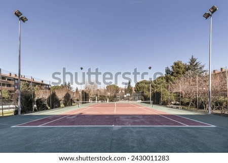 A great tennis court in the common areas of a residential complex with trees, swimming pools and recreation areas
