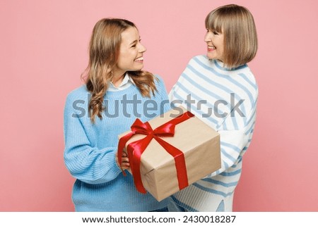 Elder happy parent mom 50s years old young adult daughter two women together wear blue casual clothes hold present box with gift ribbon bow isolated on plain light pink background. Family day concept