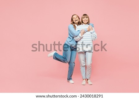 Full body smiling happy elder parent mom with young adult daughter two women together wearing blue casual clothes hug cuddle embrace isolated on plain pastel light pink background. Family day concept