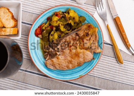 Juicy appetizing roast pork on a plate with a side dish of stewed vegetables
