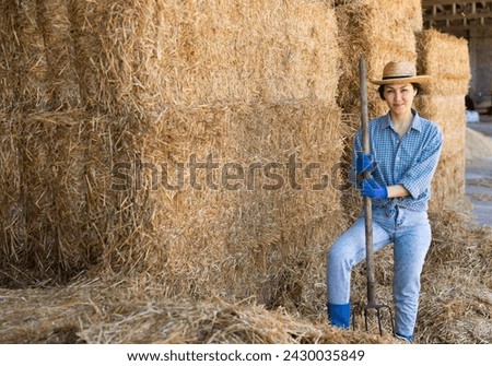 Portrait of smiling young woman farmer posing at hay storage on farm