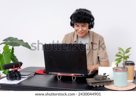 A cheerful young Asian freelance video editor works on a project at his home office while feeling motivated.