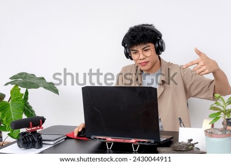 A young Asian freelance video editor with headphones dissing someone during a video conference debate.