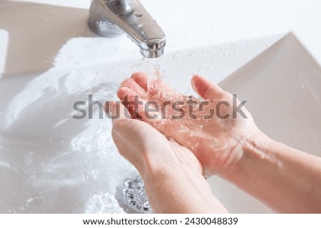 The woman washes her hands under an old crane without aerator and spends too much water. Close-up of beautiful water flow and drops Royalty-Free Stock Photo #2430048839