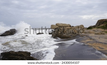 Beautiful rocky shore of muttom beach with sea waves in yellow and black sand. Royalty-Free Stock Photo #2430054107