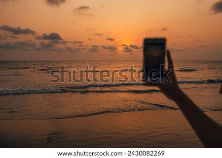 Sunset on the beach and mobile phone taking photos,golden hour