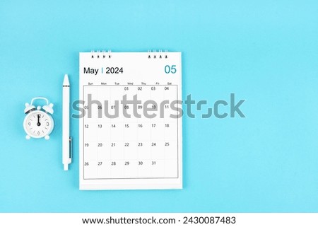 May 2024, Monthly desk calendar for 2024 year and pen with alarm clock on blue color background. Royalty-Free Stock Photo #2430087483