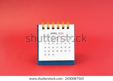 April 2024 white desk calendar on red color background.