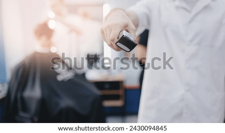 Barber shop banner. Closeup hairdresser holds hair clipper on barbershop background, with sunlight. Royalty-Free Stock Photo #2430094845