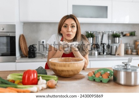 Happy attractive young adult woman lady housewife baker wear apron making dough on kitchen table baking pastry concept cooking cake biscuit doing bakery making homemade pizza at home
