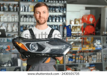 man holds automotive headlight in auto parts store. Royalty-Free Stock Photo #2430101735