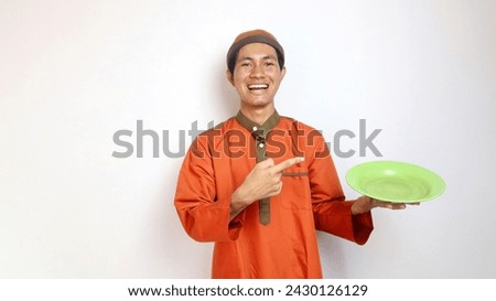 Asian Muslim man gesturing pointing to a plate in his hand with an enthusiastic expression on a white background