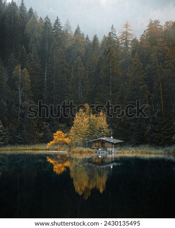 A Small Cabin Sits On The Edge Of A Lake In Austria 
