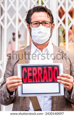 Adult professional businessman with spanish closed sign outside his store for coronavirus economy crisis emergency for lockdown at home - business recession concept with owner shop