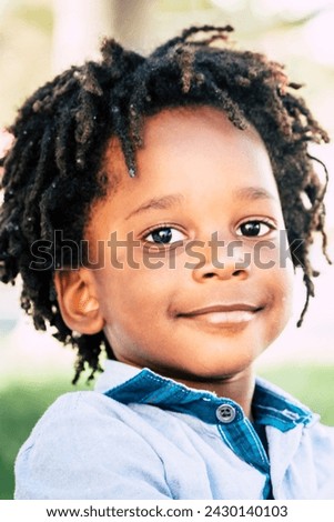 Young children black african skin play with profesisonal photo camera gear in outdoor- playful beautiful child with alternative traditional dreadlocks hair smile at the camera for happiness