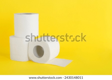Many soft toilet paper rolls on yellow background. Space for text