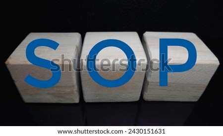 Wooden cubes with SOPs written on them are neatly lined up isolated with black background. Illustration of job instructions. Royalty-Free Stock Photo #2430151631