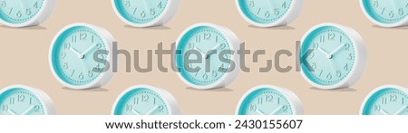 Large group of round analog table clocks with on a beige plain background. Low angle view. Web banner. Royalty-Free Stock Photo #2430155607