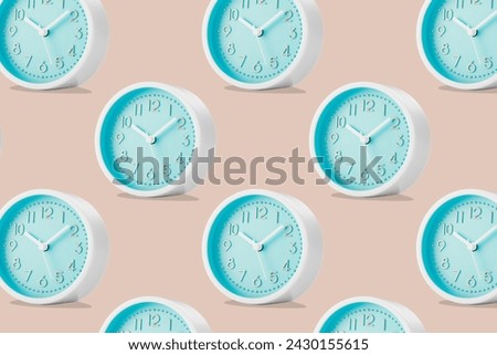 A large group of round analog table clocks with a blue dial on a beige plain background. Low angle view. Royalty-Free Stock Photo #2430155615