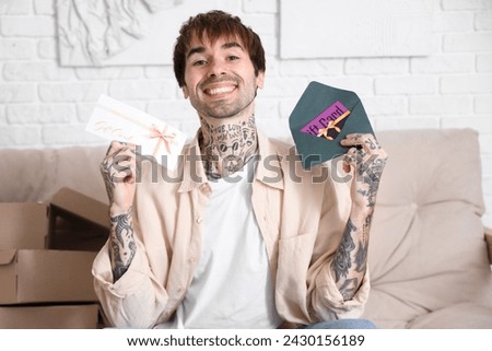 Young tattooed man with gift cards at home
