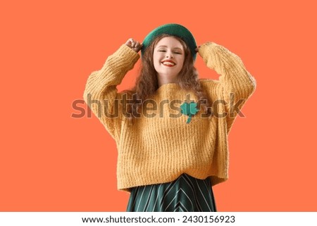 Young woman in Leprechaun's hat on orange background. St. Patrick's Day celebration