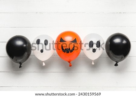 Different funny Halloween balloons on white wooden background