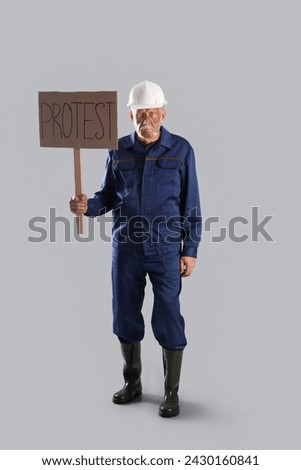Protesting miner man with placard on grey background Royalty-Free Stock Photo #2430160841