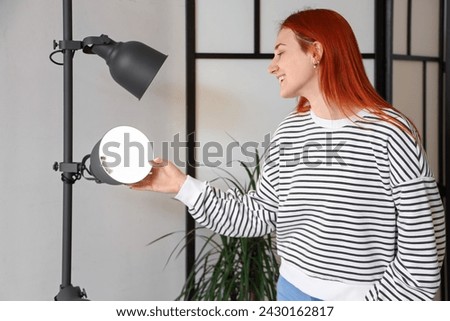 Happy young woman near glowing standard lamp at home