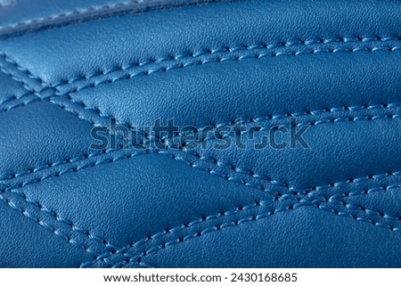 The macro texture of a blue leather sneaker with stitching. Part of the sports shoe is a close-up. Royalty-Free Stock Photo #2430168685
