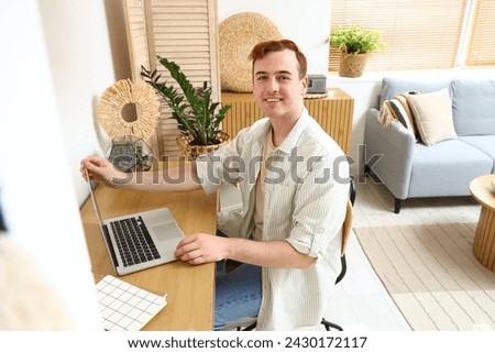 Redhead young happy man with laptop sitting at home