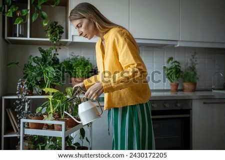 Concentrated plant lover pouring houseplants with water from watering can. Charming female growing decorative plants at home. Green ecological hobby giving stress relief, relax, joy and satisfaction Royalty-Free Stock Photo #2430172205