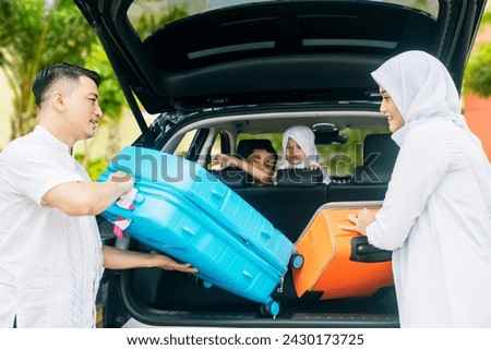 Picture of young father and mother preparing suitcases into a car for Ied Mubarak long holiday