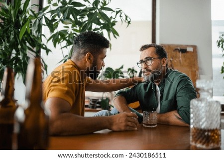 Best friends, supporting each other, drinking whiskey and talking. Discussing problems and drowning sorrows in alcohol. Concept of male friendship, bromance. Royalty-Free Stock Photo #2430186511