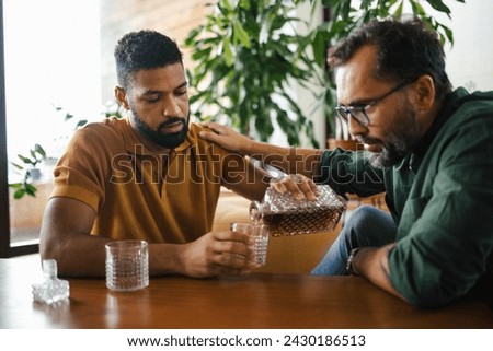 Best friends, supporting each other, drinking whiskey and talking. Discussing problems and drowning sorrows in alcohol. Concept of male friendship, bromance. Royalty-Free Stock Photo #2430186513