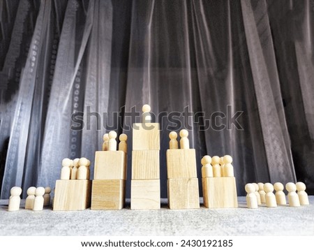 Wooden toy doll on high pedestal and many other figures below. Concept of leadership, which is not available to everyone. Victory and the winner. Talent, Recruitment employee and Successful business Royalty-Free Stock Photo #2430192185