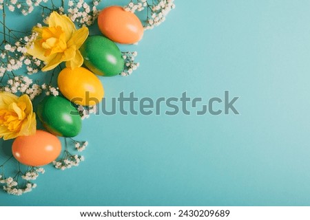 Colorful naturally dyed Easter eggs and beautiful fresh spring flowers in full bloom on pastel background, top view, flat lay style. Negative space for text.