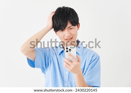 Asian man with the smartphone holding his head in white background