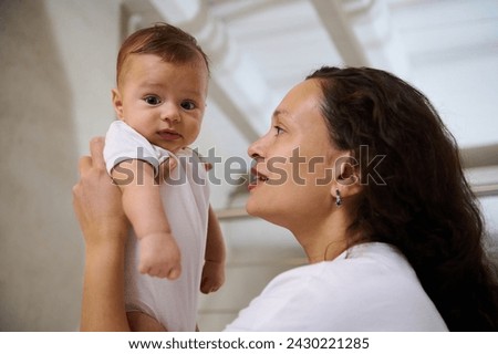 Side view of a happy smiling woman mother holding her baby boy in her arms. The concept of Mother's Day. World Children's protection Day. Babyhood. Infancy. Baby care and childcare. Close-up portrait. Royalty-Free Stock Photo #2430221285