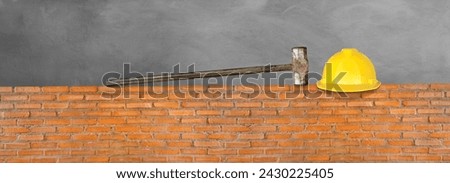 Helmet and hammer on red brick wall. Cement background.