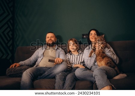 Family Sitting On Sofa In Open Plan Lounge Watching Television. High quality photo