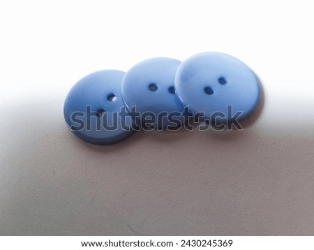 close-up of three blue sewing buttons in a row isolated on a white background