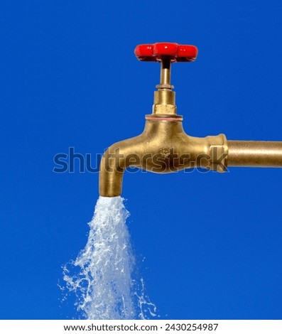 closeup of a golden brass water tap with red handle, water  running out of it Royalty-Free Stock Photo #2430254987