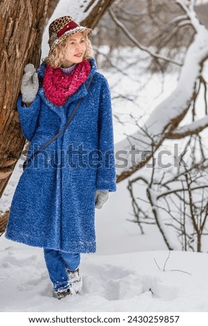 Close-up portrait of a young beautiful blonde woman against the background of a winter snow-covered forest.