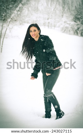  view of happy brunette girl playing with snow in winter landscape. Beautiful young female on winter background.Happy beautiful young woman in warm soft clothes outdoor in a winter day