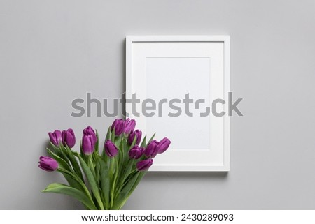 Blank picture frame mockup with tulips flowers decor, white frame on grey wall background