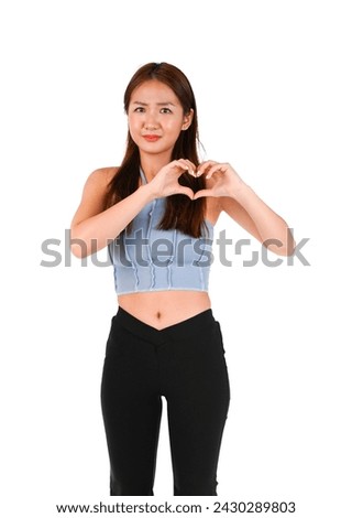 Serious young asian woman doing a heart gesture with both hands against a white background